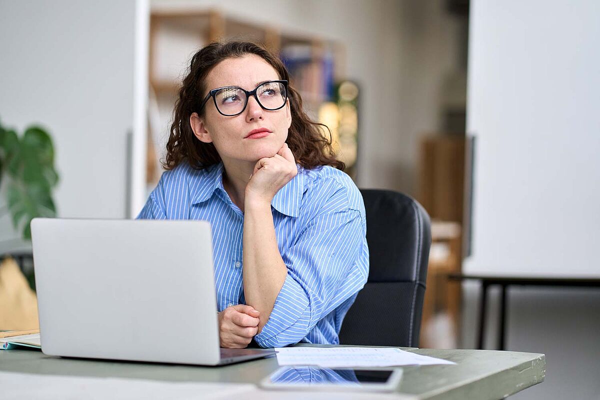 Frau grübelt vor offenem Laptop